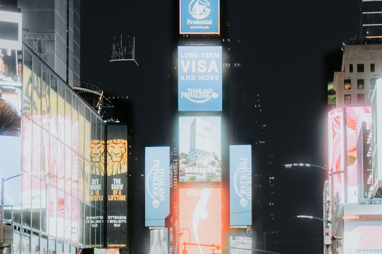 Reclamezuilen vol grote merken op Times Square bij nacht; de billboards in kleur, de stad in grijs
